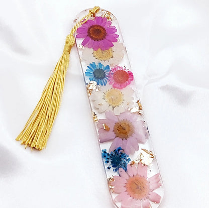 Marque-pages en résine époxy. Transparent avec fleurs multicolores et feuille d'or. Pompon gland soyeux doré. PRETTY RESINE