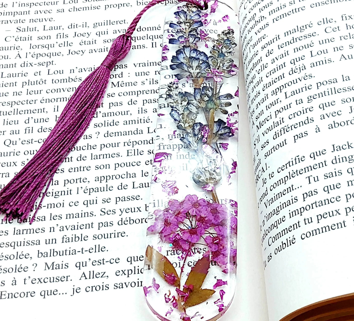 Marque-pages en résine époxy. Fleurs violettes. Posé dans un livre.