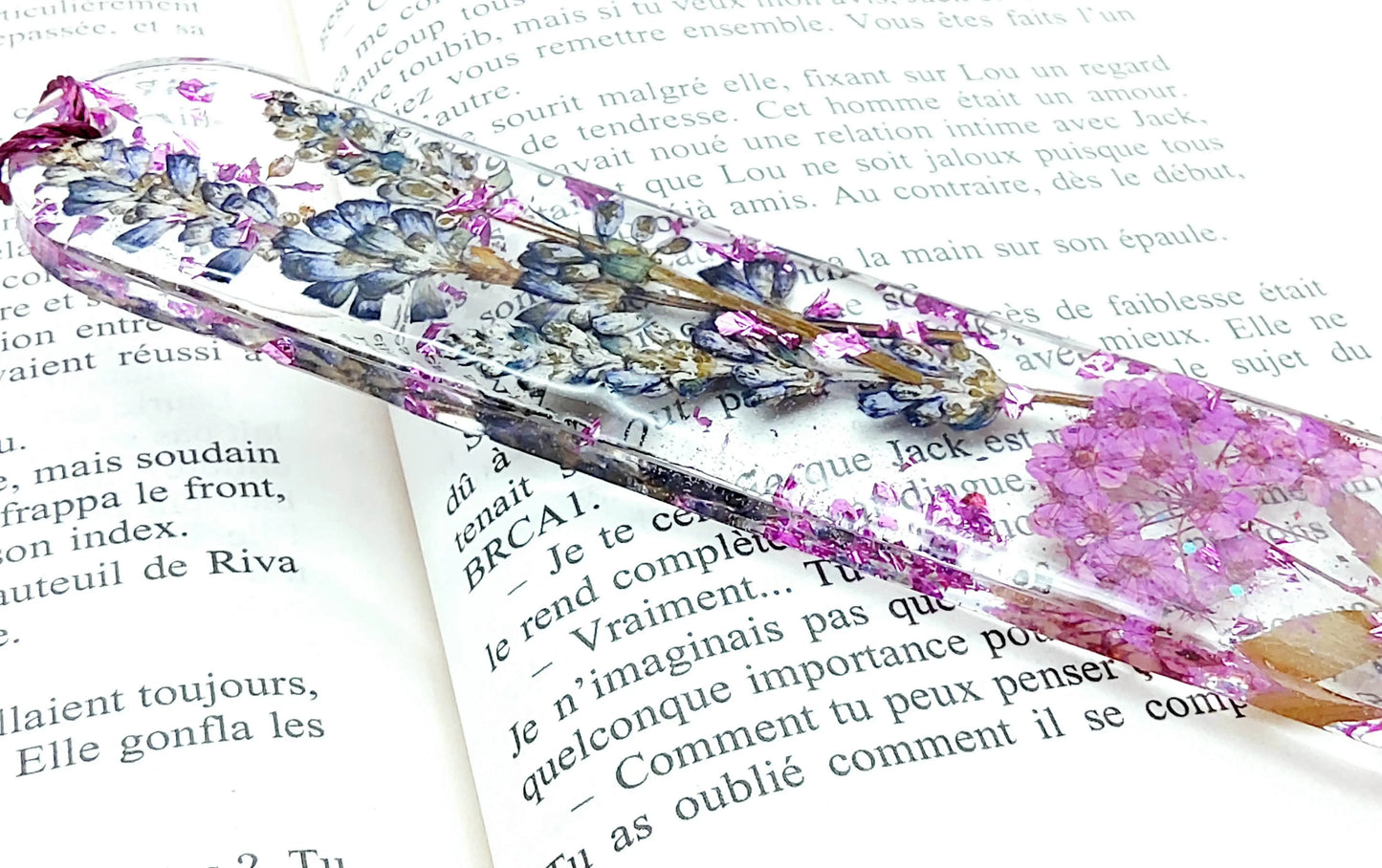 Marque-pages en résine époxy. Fleurs violettes. Posé dans un livre Vue de côté.