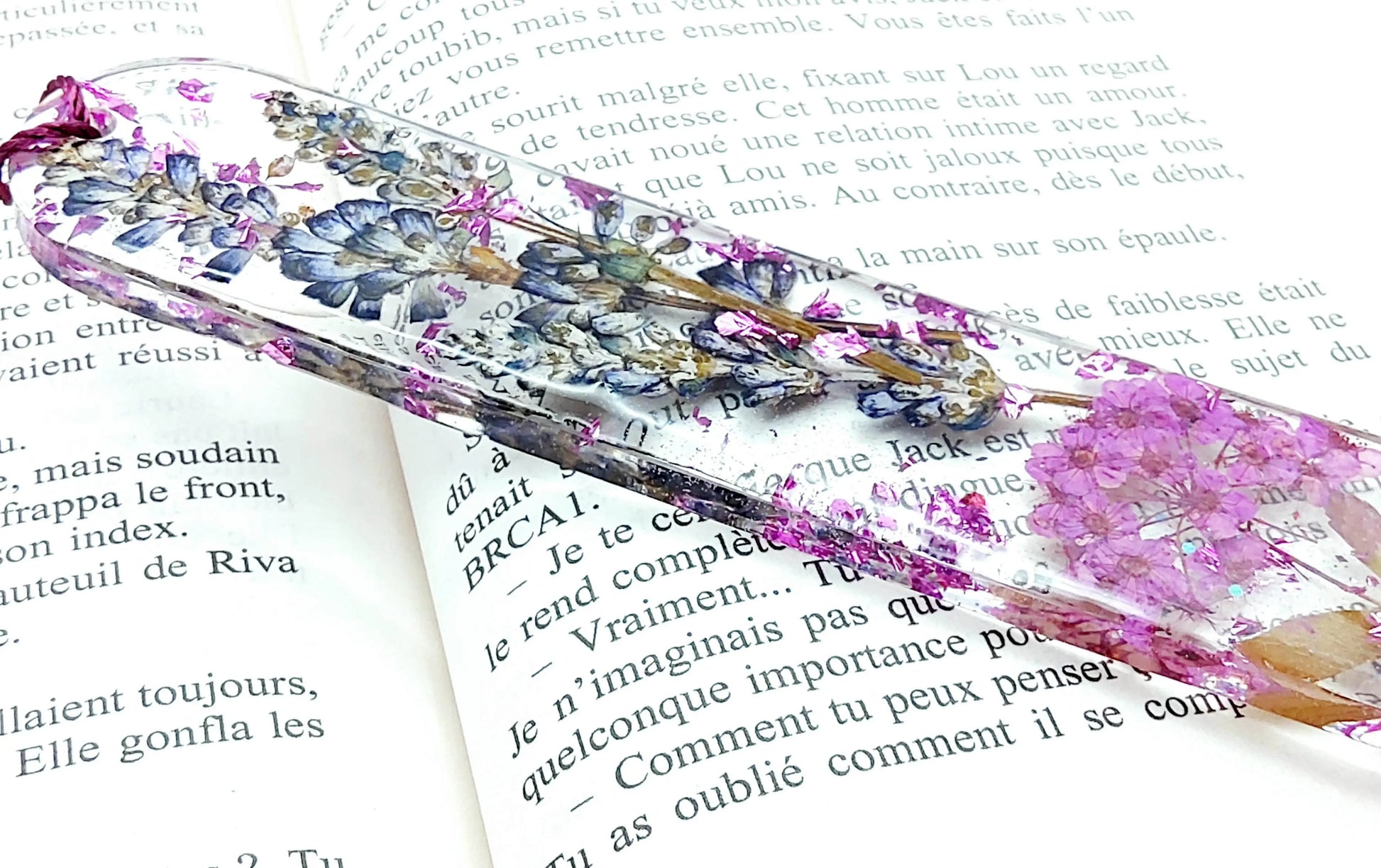 Marque-pages en résine époxy. Fleurs violettes. Posé dans un livre Vue de côté.