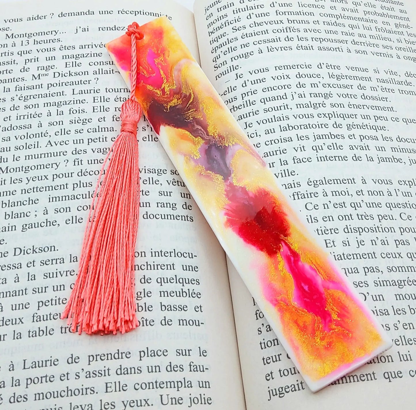 Marque-pages en résine époxy, multicolore, effet marbré rose et doré, posé dans un livre