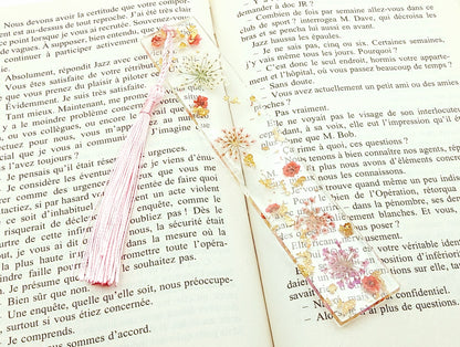 Marque-pages en résine et petites fleurs séchées roses, posé dans un livre