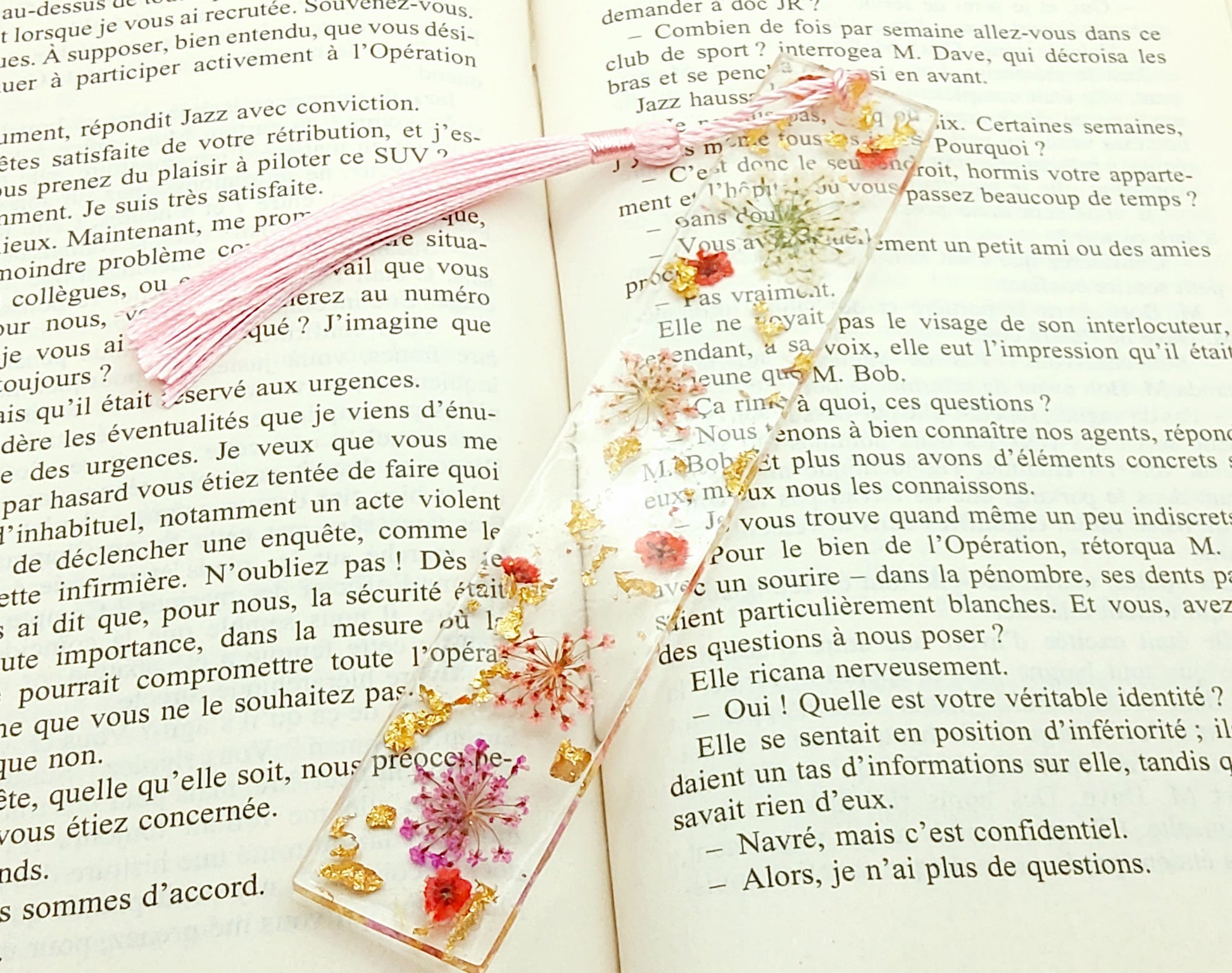 Marque-pages en résine et petites fleurs séchées roses, posé dans un livre