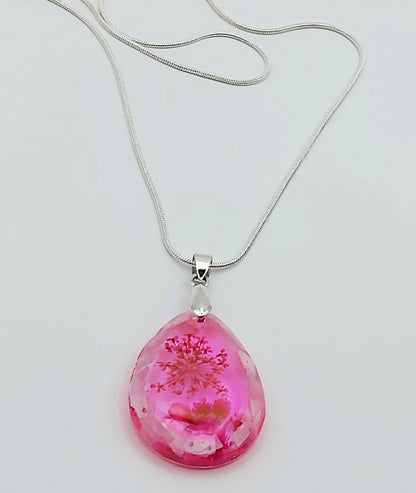 Pendentif "Goutte d'eau" en résine époxy et sa chaîne argentée. Fleurs et morceaux de coquillages roses.