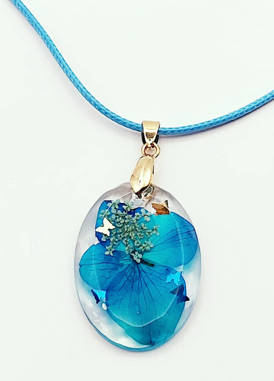 Pendentif OVALE en résine époxy. Fleurs bleue et blanche. Cordon en coton ciré bleu. PRETTY RESINE