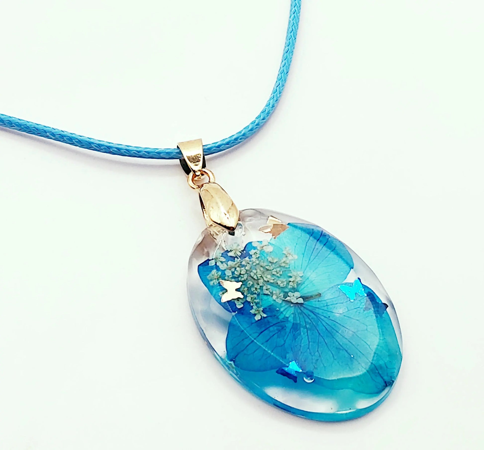 Pendentif OVALE en résine époxy. Fleurs bleue et blanche. Cordon en coton ciré bleu. PRETTY RESINE