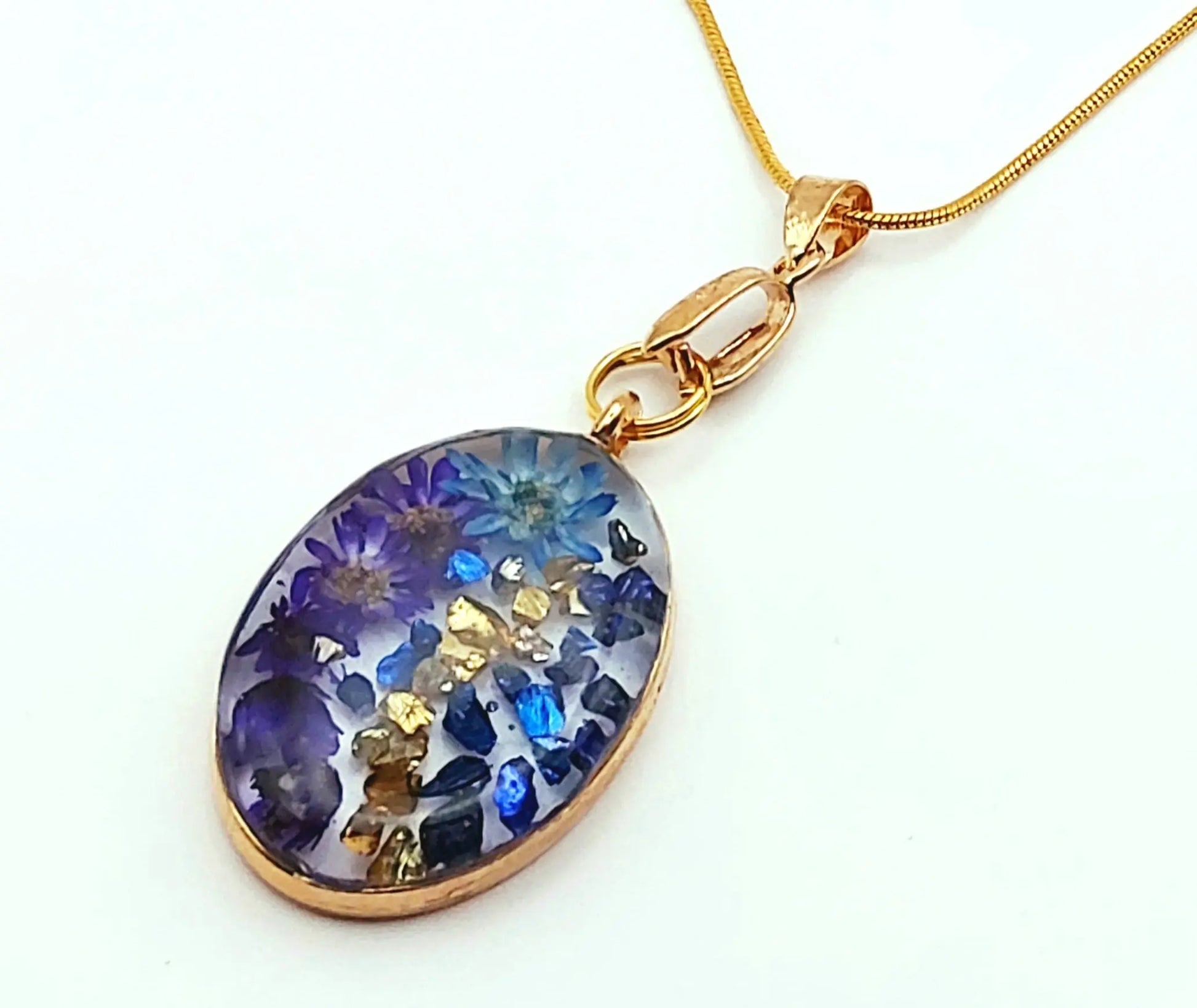 Pendentif Ovale en résine et sa chaîne dorée. Fleurs bleues.