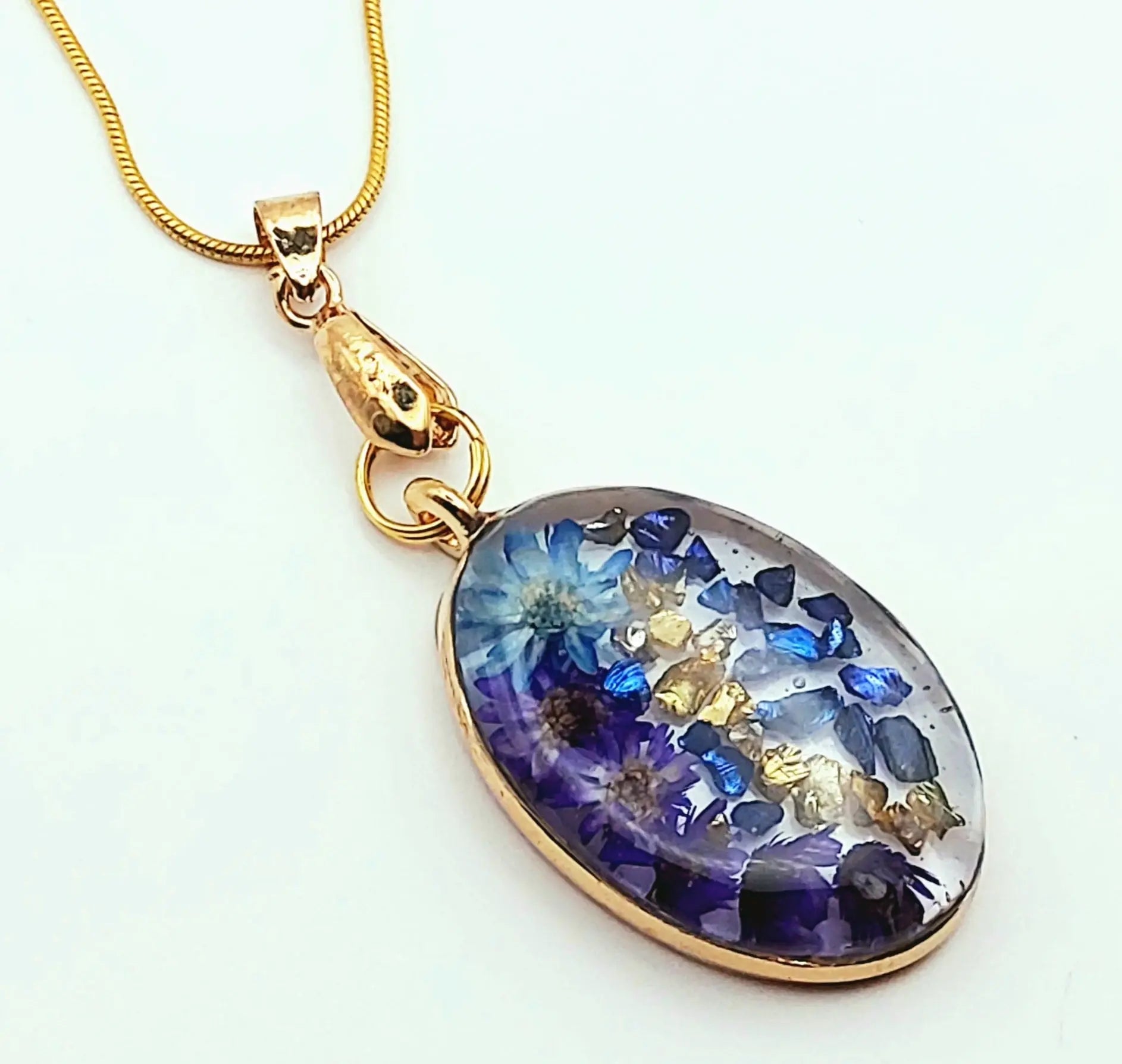 Pendentif Ovale en résine et sa chaîne dorée. Fleurs bleues.