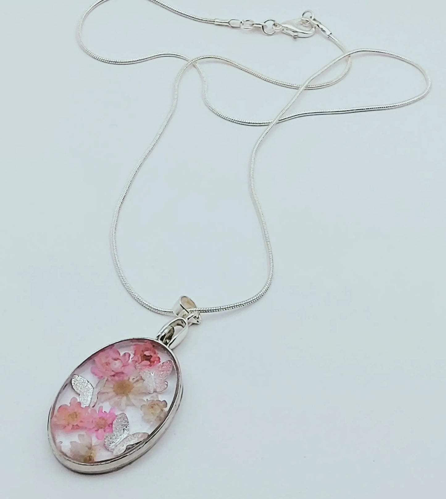 Pendentif Ovale orné de fleurs séchées roses et de papillons argentés - PRETTY RESINE