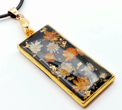 Pendentif Rectangulaire orné de fleurs séchées - Doré, fond noir, fleurs oranges et blanches - Cordon en coton ciré noir - PRETTY RESINE