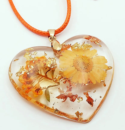 Pendentif "Coeur fleuri" en résine époxy, fleurs oranges. Feuille or et cuivre. Gros plan.