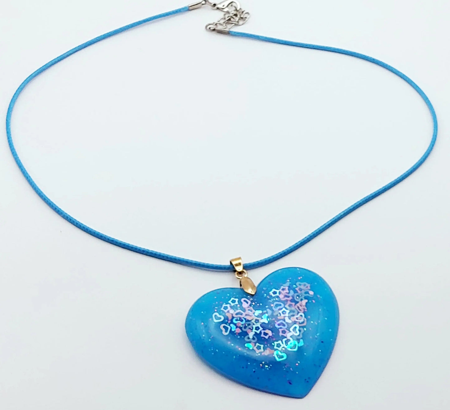 Pendentif "Coeur" en résine époxy, bleu avec paillettes coeurs et étoiles. Cordon bleu. Plan large.