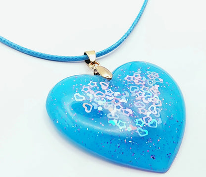 Pendentif "Coeur" en résine époxy, bleu avec paillettes coeurs et étoiles. Cordon bleu. Plan serré.