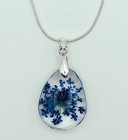 Pendentif "Goutte d'eau" en résine et sa chaîne, fleur bleue, gros plan.