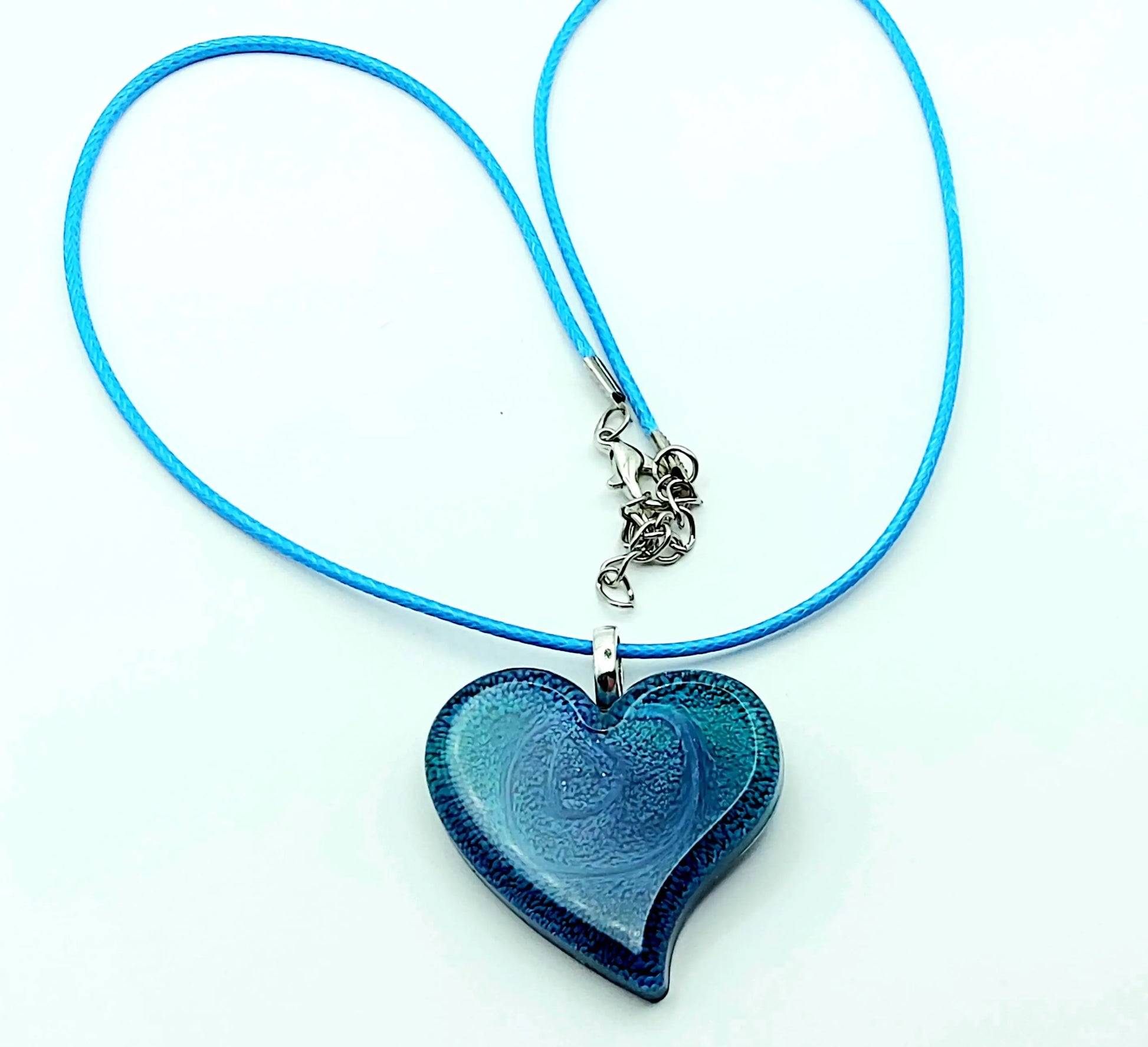 Pendentif Petit Coeur en résine époxy, effet pétri bleu. Cordon en coton ciré bleu. Plan large.