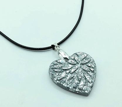 Pendentif "Petit Coeur" en résiné époxy, paillettes argentées, cordon en coton ciré noir. Vue de côté.