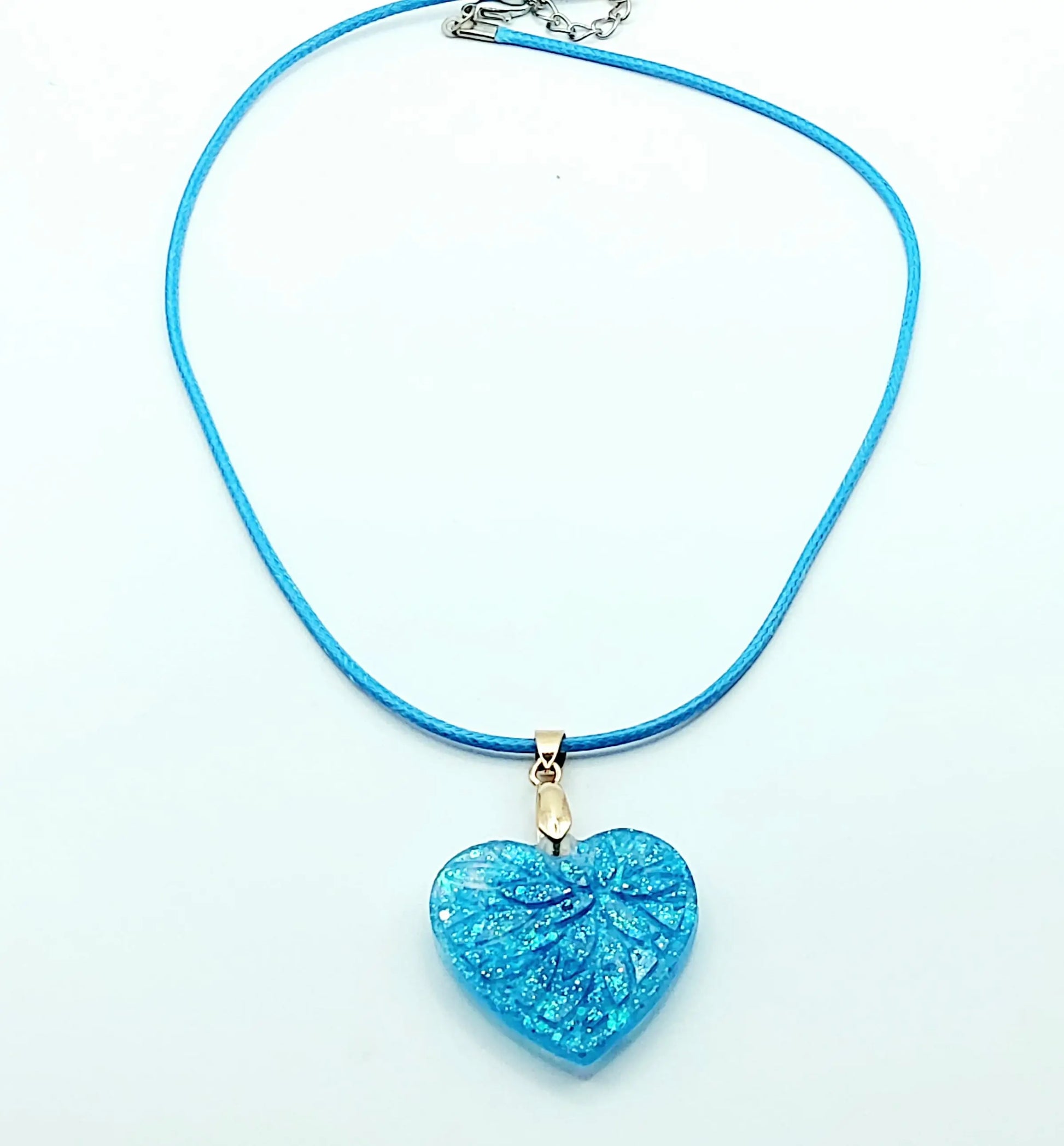 Pendentif "Petit Coeur" en résine époxy, paillettes bleues. Cordon en coton ciré bleu. Plan large.