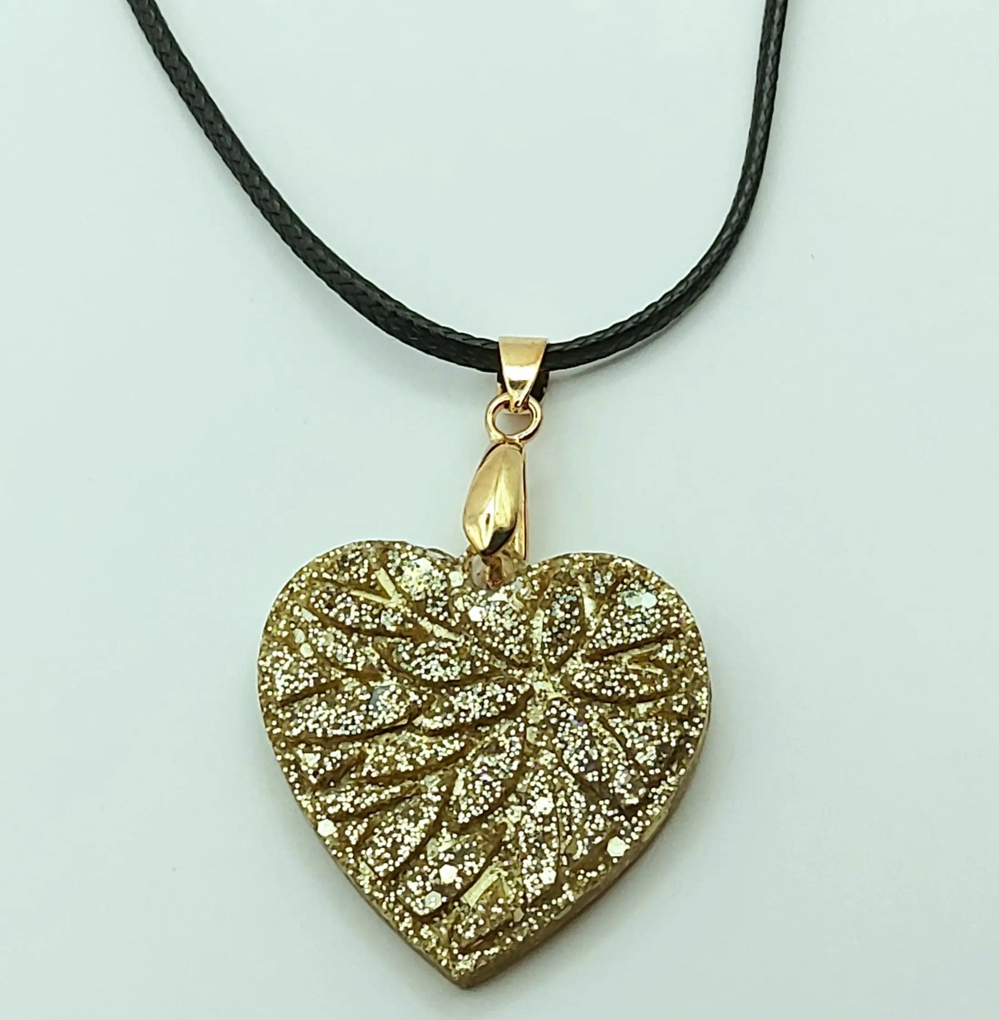 Pendentif "Petit Coeur" en résine époxy, paillettes dorées. Gros plan.