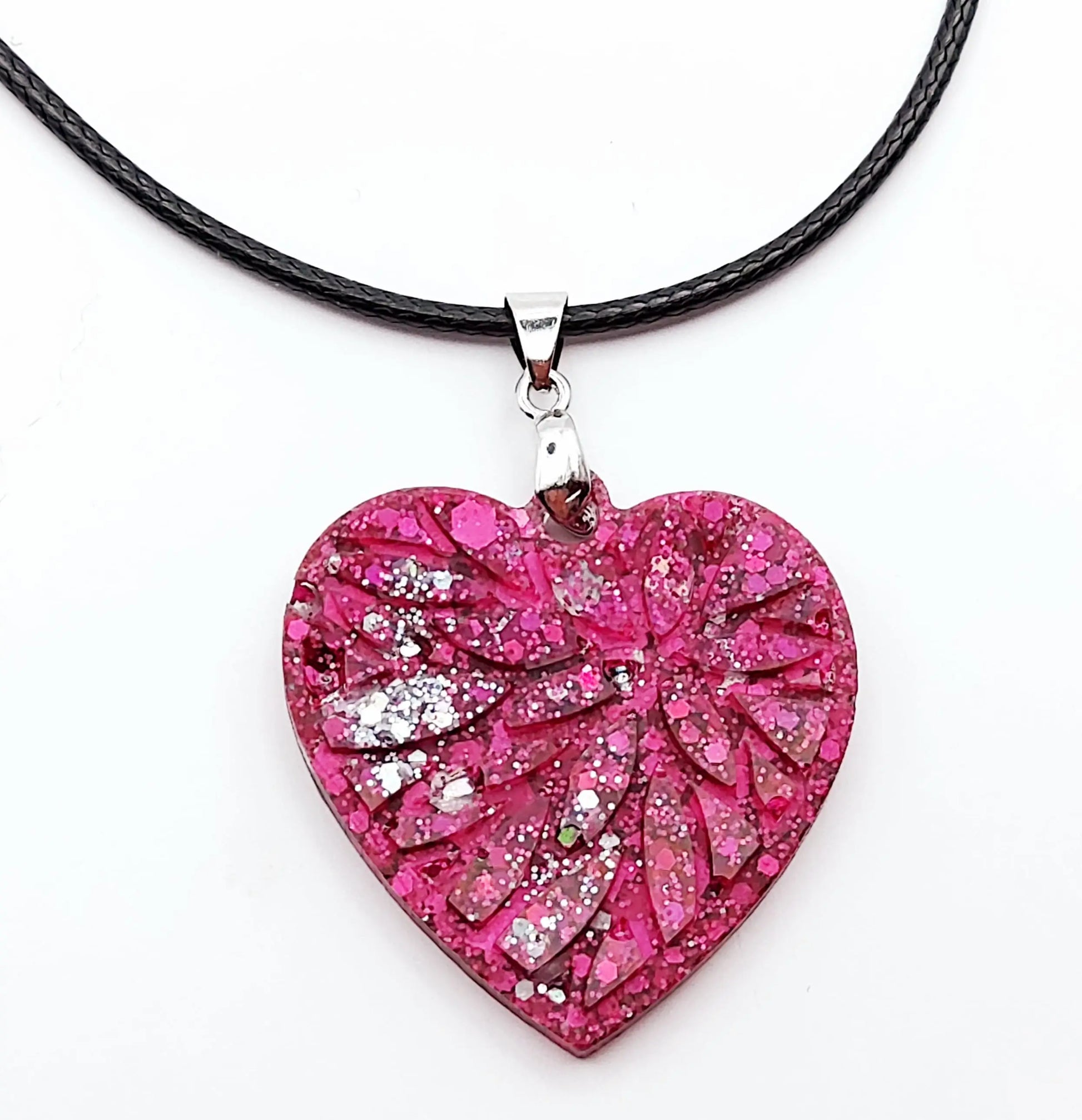 Pendentif "Petit Coeur" en résine époxy, paillettes fuchsia et argent. Gros plan.