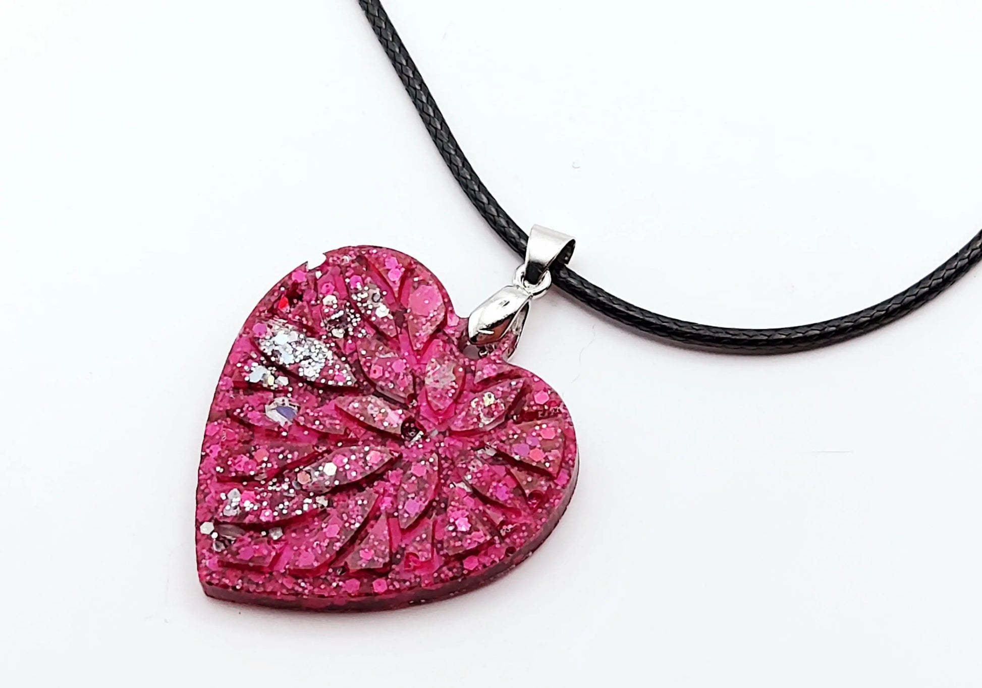 Pendentif "Petit Coeur" en résine époxy, paillettes fuchsia et argent. Gros plan.