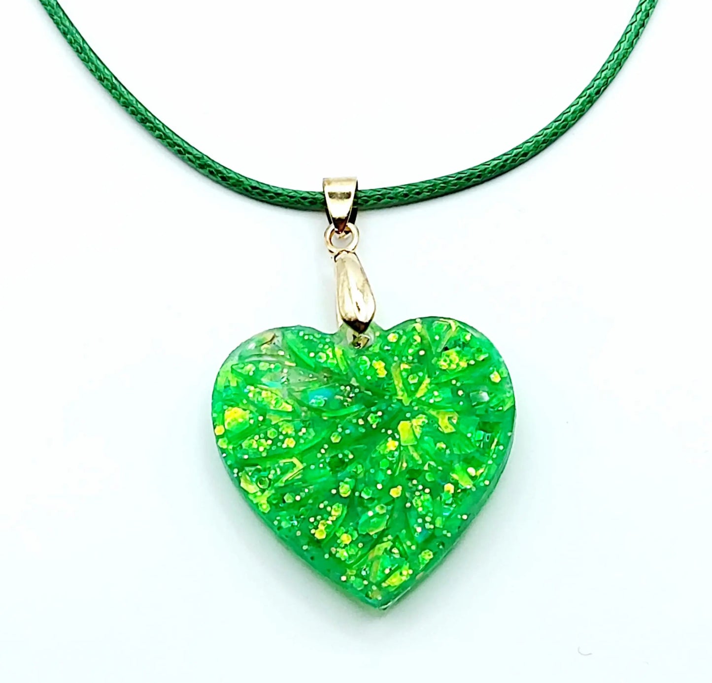 Pendentif "Petit Coeur" en résine époxy, paillettes vertes. Cordon en coton ciré vert. Gros plan.