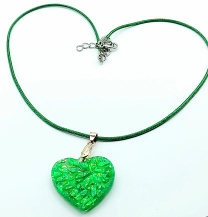 Pendentif "Petit Coeur" en résine époxy, paillettes vertes. Cordon en coton ciré vert. Plan large.