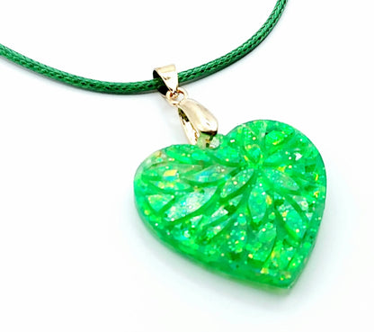 Pendentif "Petit Coeur" en résine époxy, paillettes vertes. Cordon en coton ciré vert. Gros plan.