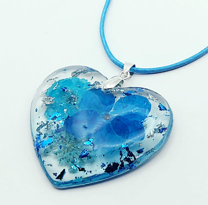 Pendentif "Coeur Fleuri" en résine époxy, fleurs et cordon en coton ciré bleus, gros plan.