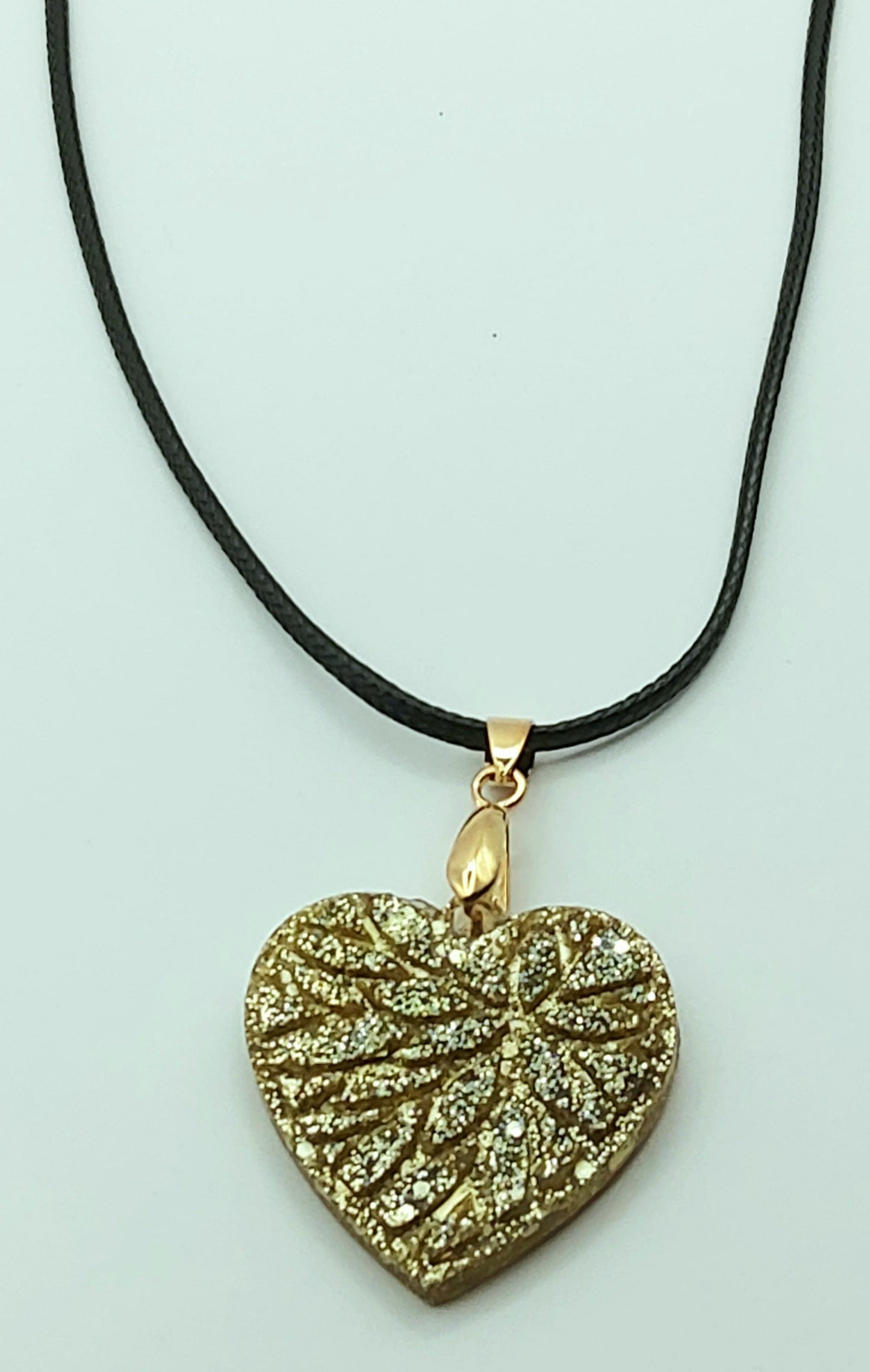 Pendentif "Petit Coeur" en résine époxy, paillettes dorées. Cordon en coton ciré noir.