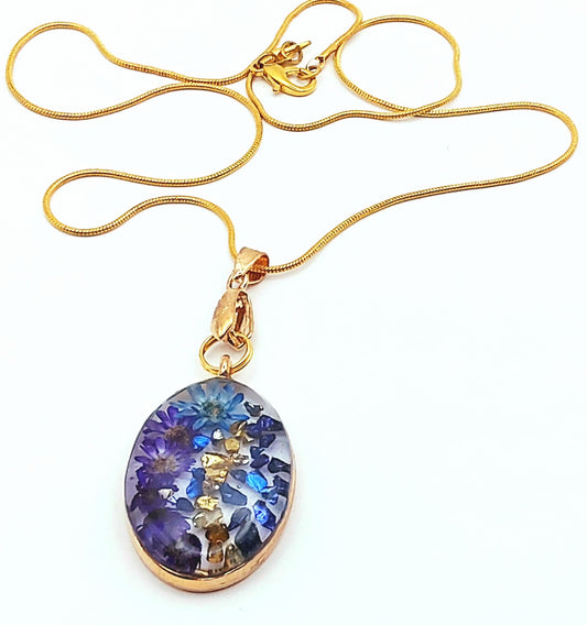 Pendentif Ovale en résine et sa chaîne dorée. Fleurs bleues.