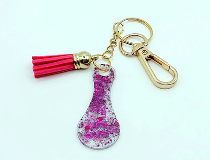 Porte-clés Jeton de caddie en résine époxy, blanc irisé et paillettes fuchsia. Pompon gland rose fuchsia, Anneau et mousqueton doré.