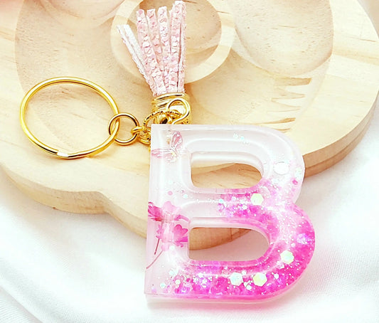Porte-clés LETTRE B en résine époxy. Fond blanc. Paillettes, fleurs et papillon roses. PRETTY RESINE