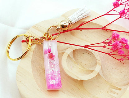 Porte-clés LETTRE I en résine époxy. Fond blanc. Paillettes, fleurs et papillon rose. Pompon gland pailleté blanc - PRETTY RESINE