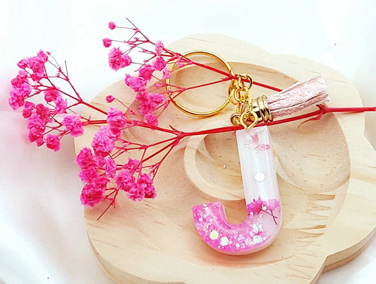 Porte-clés LETTRE J en résine époxy. Fond blanc, paillettes, fleurs et papillon roses. Pompon gland pailleté rose - PRETTY RESINE