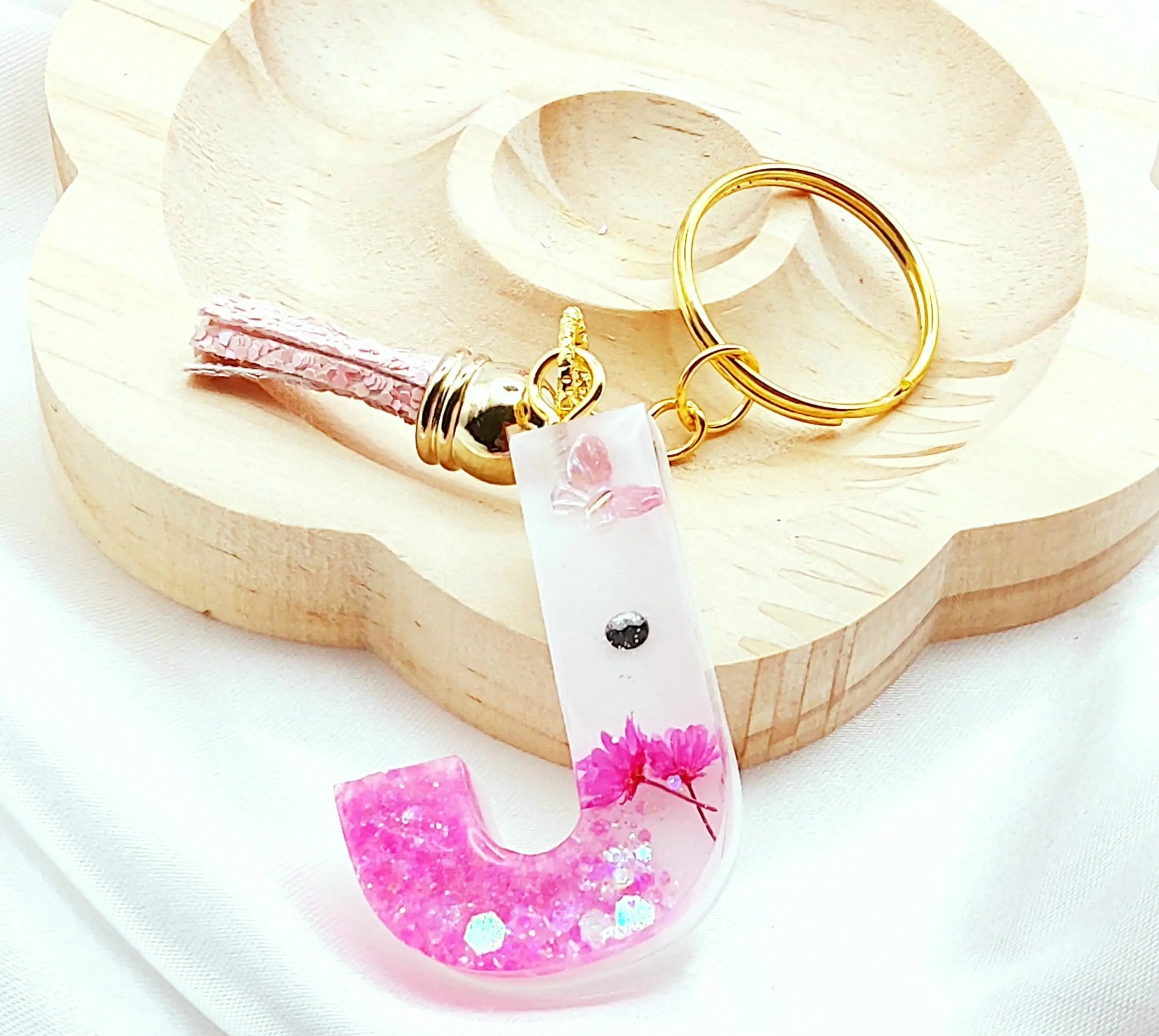 Porte-clés LETTRE J en résine époxy. Fond blanc, paillettes, fleurs et papillon roses. Pompon gland pailleté rose - PRETTY RESINE