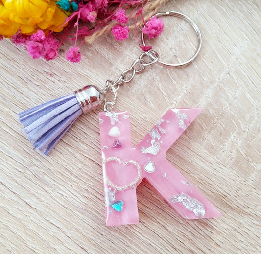 Porte-clés Lettre K en résine époxy. Rose et inserts argentés. Pompon gland mauve. PRETTY RESINE