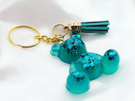 Porte-clés OURSON ASSIS en résine époxy. Vert avec paillettes. Anneau doré. Pompon gland vert