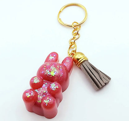 Porte-clés "Lapin Mignon" en résine époxy. Rose et paillettes holographiques. Anneau doré. Pompon gland gris clair.