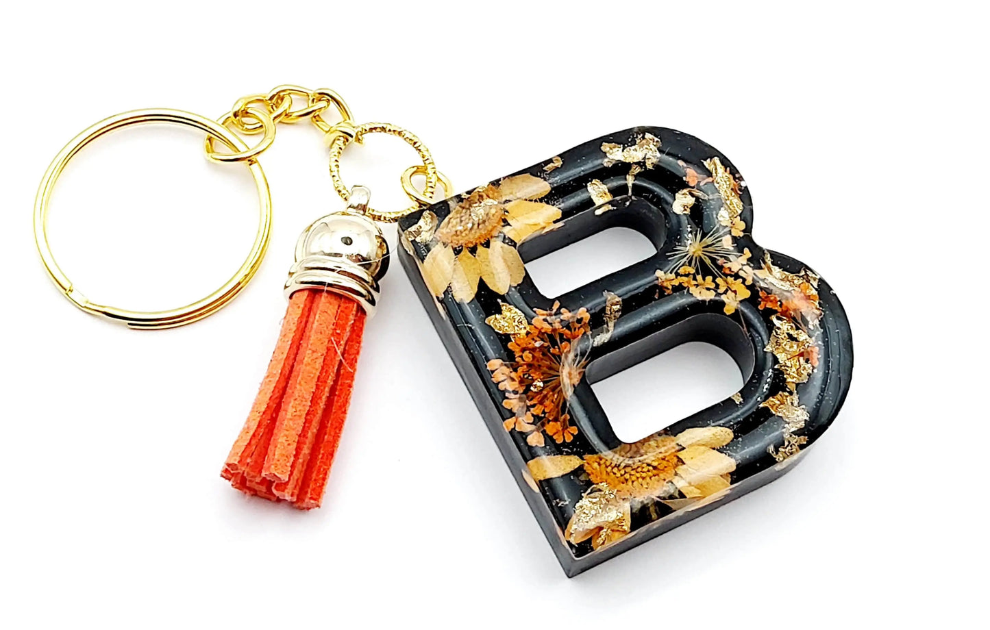 Porte-clés "Lettre B" en résine époxy. Noir , fleurs oranges et feuille d'or. Anneau doré. Pompon gland orange.