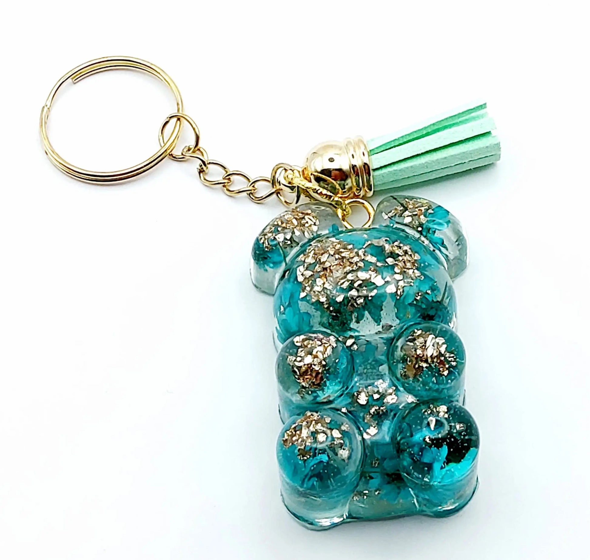 Porte-clés "Ourson debout" en résine époxy. Fleurs turquoises et verre pilé doré. Anneau doré et pompon gland vert pastel.