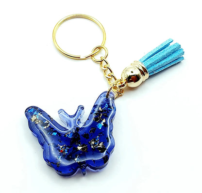 Porte-clés "Papillon" en résine époxy. Bleu et feuille d'or. Anneau doré. Pompon gland bleu ciel.