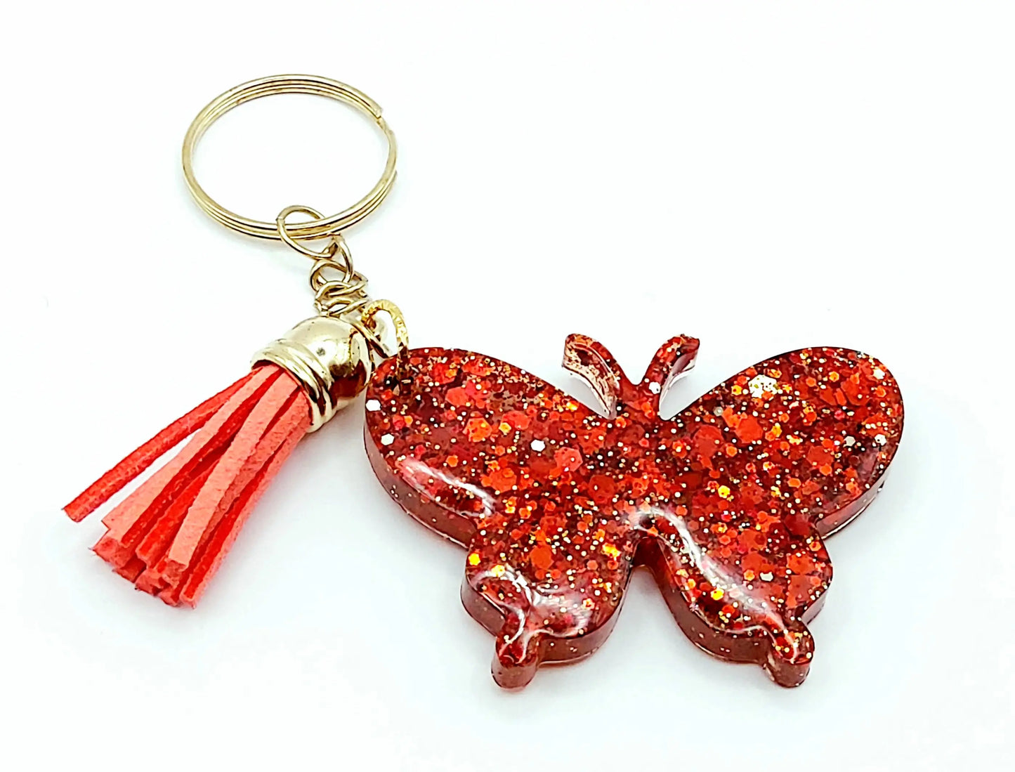 Porte-clés "Papillon" en résine époxy. Paillettes rouges, anneau doré, pompon gland rouge.