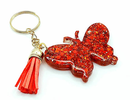 Porte-clés "Papillon" en résine époxy. Paillettes rouges, anneau doré, pompon gland rouge.