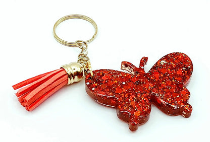 Porte-clés "Papillon" en résine époxy. Paillettes rouges, anneau doré, pompon gland rouge.