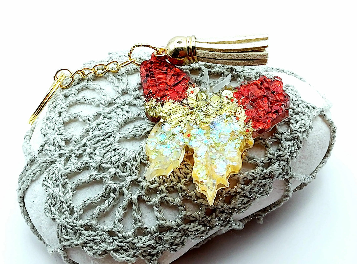 Porte-clés "Papillon" en résine époxy, paillettes rouges et or. Anneau doré, pompon gland beige. Posé sur un galet.