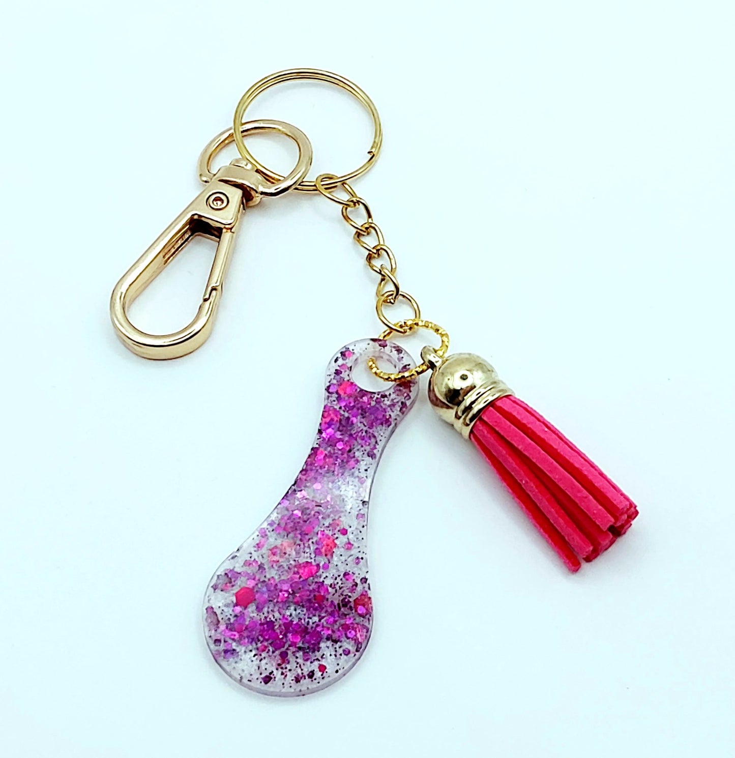 Porte-clés Jeton de caddie en résine époxy, blanc irisé et paillettes fuchsia. Pompon gland rose fuchsia, Anneau et mousqueton doré.