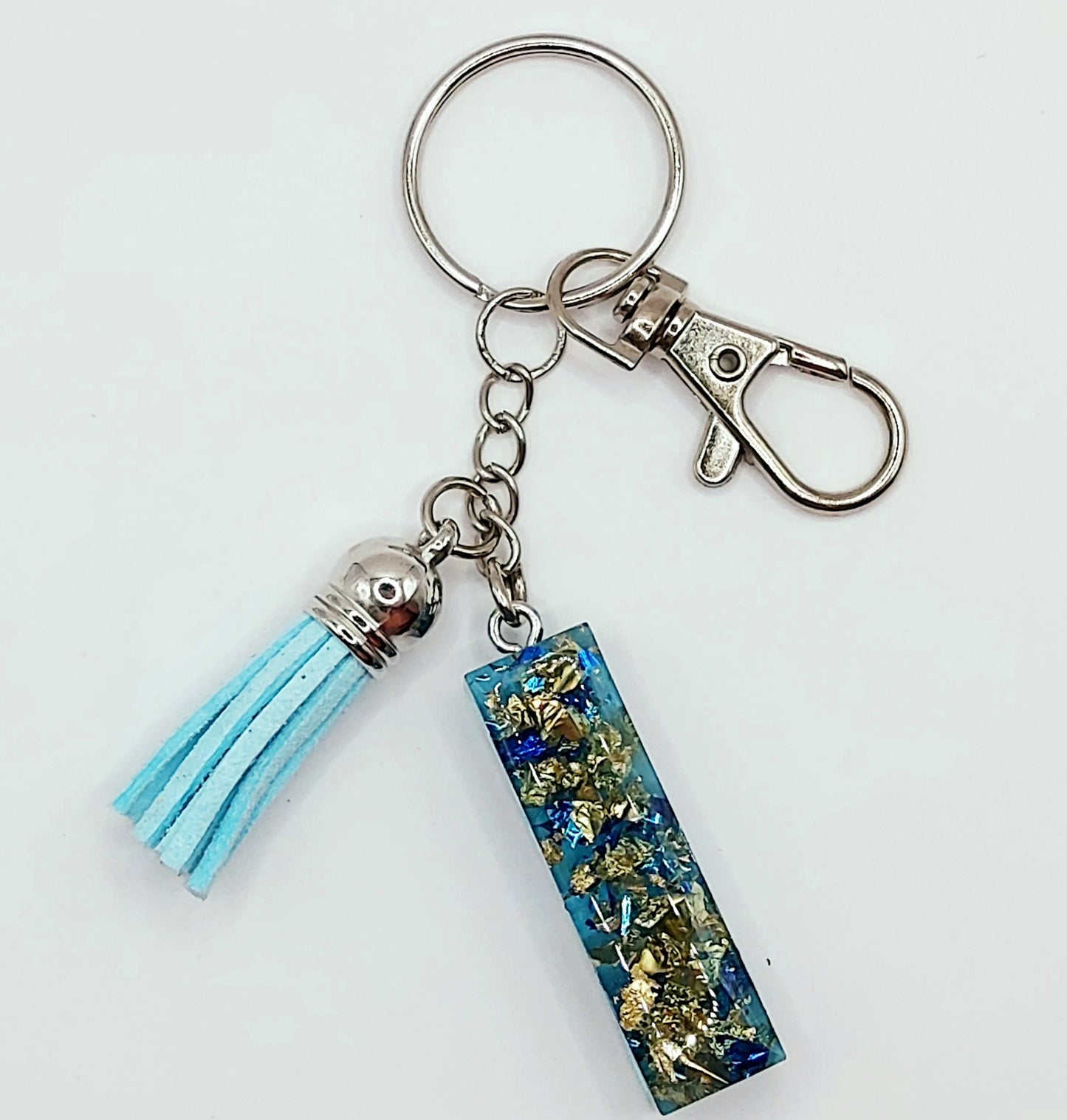 Porte-clés "Lettre I" en résine époxy, bleu et feuille d'or. Pompon gland bleu ciel. Anneau et mousqueton argentés.