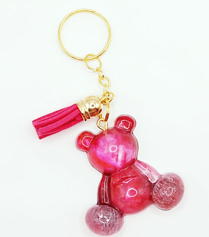 Porte-clés "Ourson assis" en résine époxy, rose, effet pétri. Anneau doré. Pompon gland fuchsia.