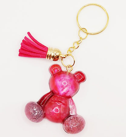 Porte-clés "Ourson assis" en résine époxy, rose, effet pétri. Anneau doré. Pompon gland fuchsia.