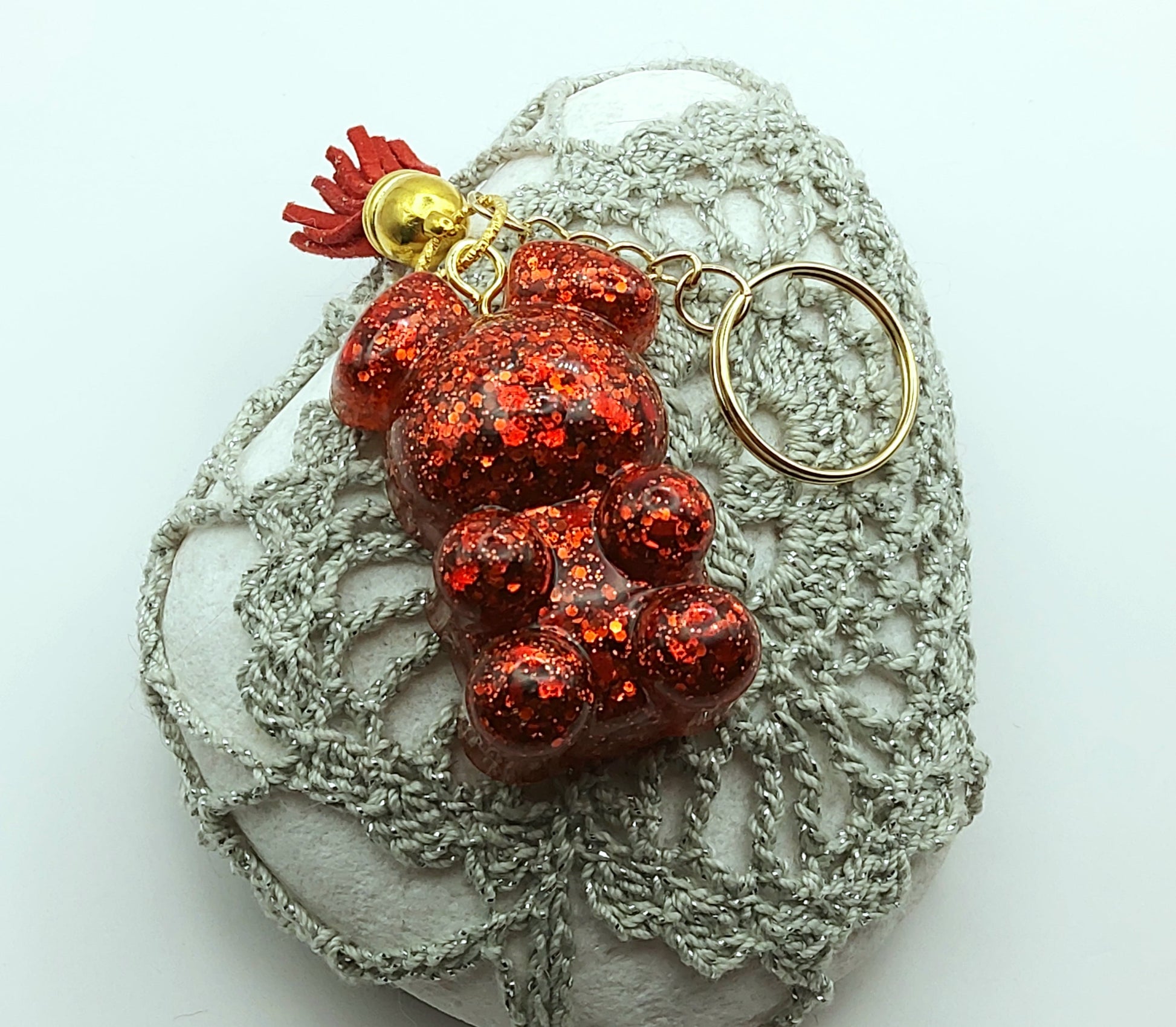 Porte-clés "Ourson debout" en résine époxy, paillettes rouges, pompon gland rouge, anneau doré. Posé sur un galet.